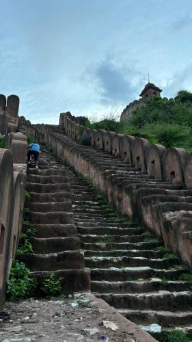 a set of stone stairs with a person sitting on top at House of Amer in Jaipur