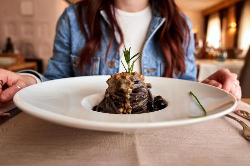 a woman sitting at a table with a plate of food at Hotel Ristorante Pennar in Asiago