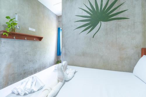 a bedroom with a white bed with a plant on the wall at Sinag Hostel in General Luna