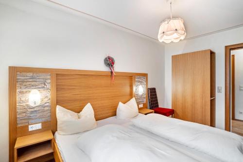 a bedroom with a large white bed and a red chair at Wein- und Klimahotel Bergfriedel in Bühlertal