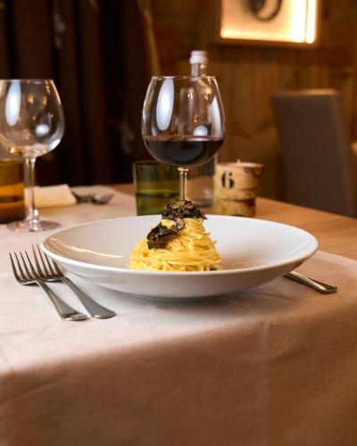a plate of food and a glass of wine on a table at Hotel Ristorante Pennar in Asiago