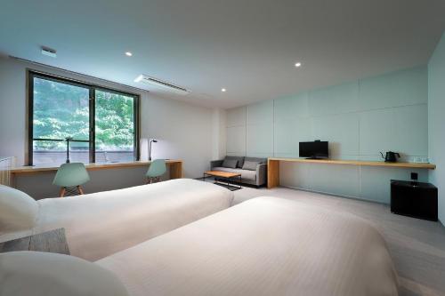 a room with two beds and a couch and a window at Shin Toji Hotel Lulud in Nakanojo