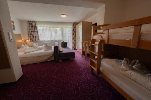 a hotel room with two bunk beds and a couch at Alpenpension Regina in Nauders