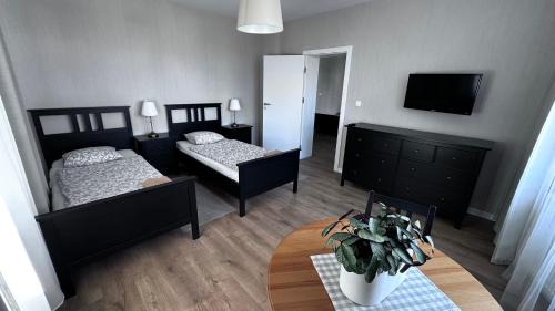 a bedroom with two beds and a table and a tv at Belgard- House 32 in Białogard