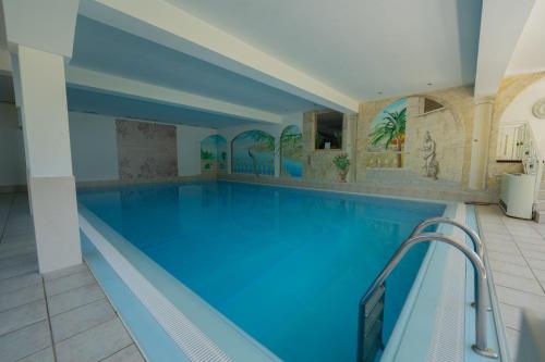 a large swimming pool with blue water in a building at Alpenpension Regina in Nauders