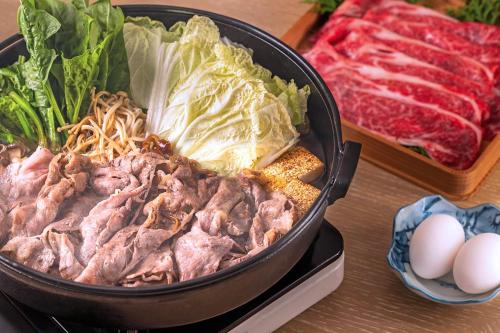 a pan filled with meat and lettuce and eggs on a table at Shin Toji Hotel Lulud in Nakanojo
