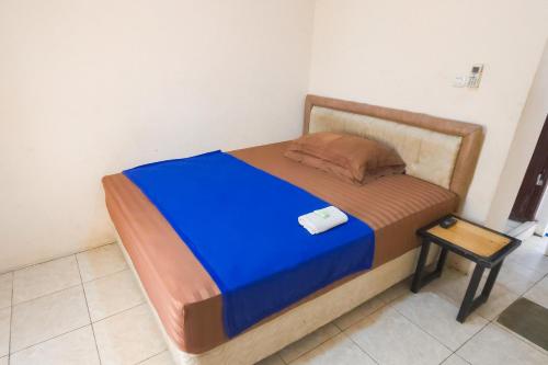 a bed in a room with a blue blanket and a stool at RedDoorz at Fortune Hotel Jalan Walanda Maramis Manado in Manado
