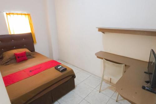 a small bedroom with a bed and a desk at RedDoorz at Fortune Hotel Jalan Walanda Maramis Manado in Manado
