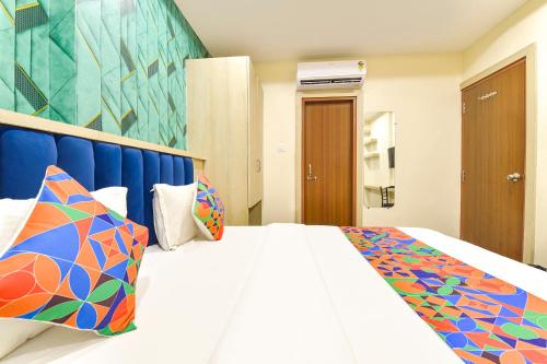 Un dormitorio con una gran cama blanca con almohadas de colores. en FabHotel Bhavna Palace, en Indore
