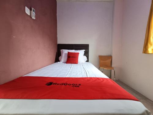 a bedroom with a bed with a red blanket on it at RedDoorz at Fortune Hotel Jalan Walanda Maramis Manado in Manado