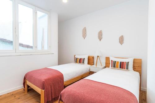 two beds in a room with two windows at CICIOSO flats João de Deus 1 in Évora