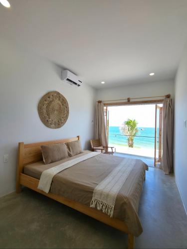 a bedroom with a bed with a view of the ocean at Kihu Home Phan Thiet in Bình Sum
