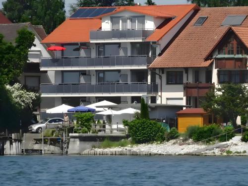 a building with an orange roof next to the water at Gästehaus D i c k r e i t e r in Immenstaad am Bodensee