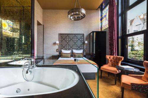a large bathroom with a tub and a bed at The Pavilions Amsterdam, The Toren in Amsterdam