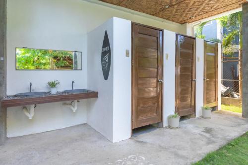 a bathroom with two sinks and a surfboard on a wall at Sinag Hostel in General Luna