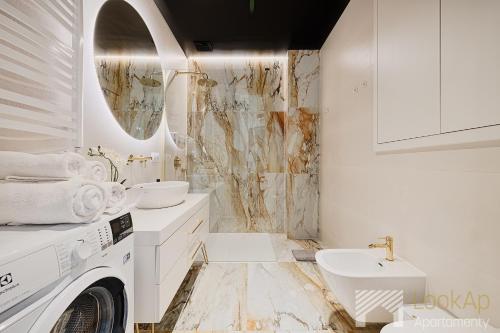 a white bathroom with a sink and a washing machine at Jaracza Exclusive by LookAp - darmowy parking w centrum!! in Łódź