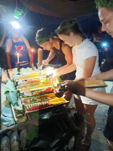 a group of women standing around a buffet of food at Amornkeeree Khao Sok Camping in Khao Sok