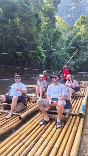 a group of people sitting on a bamboo raft at Amornkeeree Khao Sok Camping in Khao Sok