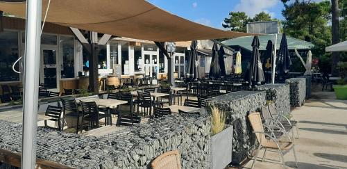 a restaurant with tables and chairs and umbrellas at MOBIL HOME CONFORT PLUS - 40m2 - 3ch - 2 SDB - Camping 4 étoiles - BONNE ANSE 56 in Les Mathes