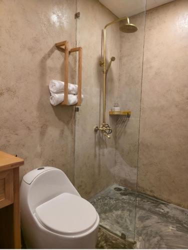 a bathroom with a toilet and a glass shower at Kihu Home Phan Thiet in Bình Sum