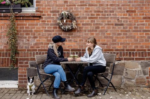 two women sitting at a table in front of a brick wall at Gutshof Zum Adlernest in Arnsnesta