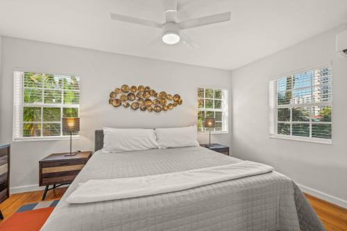 a white bedroom with a bed and two windows at Condo by the Beach King Bed Lush Patio w BBQ Breakers Key Seven H0MES in Fort Lauderdale