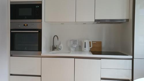 a white kitchen with a sink and a microwave at University City Heart, Tartu Home in Tartu