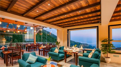 a restaurant with blue chairs and tables and large windows at Jr Hotel Dharamshala in Dharamshala