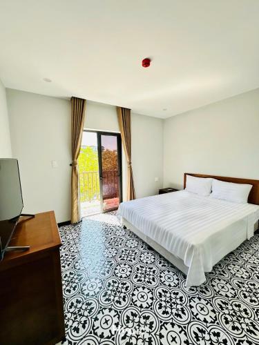 a bedroom with a white bed and a television at Laa House in Hoi An