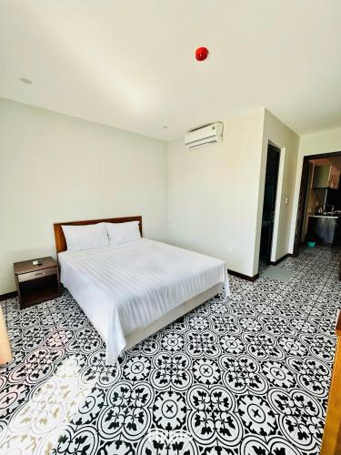 a bedroom with a white bed and a black and white floor at Laa House in Hoi An