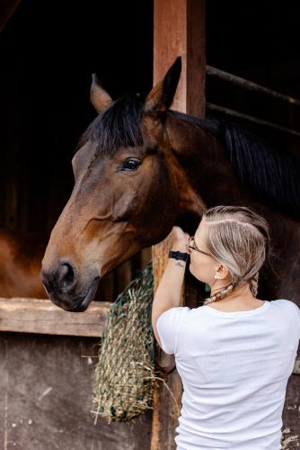 a woman is petting a horse in a stable at Gutshof Zum Adlernest in Arnsnesta