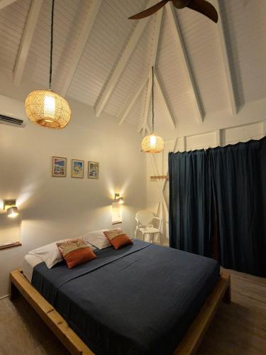a bedroom with a large bed with blue sheets at Bois Coco in Terre-de-Haut