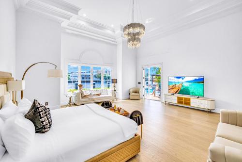 ein weißes Schlafzimmer mit großem Bett und ein Wohnzimmer in der Unterkunft Waterfront Luxury Villa Heated Pool with Afternoon Sun Coral Key in Fort Lauderdale