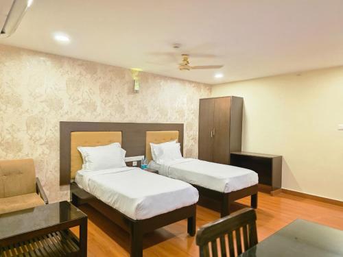 a hotel room with two beds and a table at MG Beatle Hotel Tirupati in Tirupati