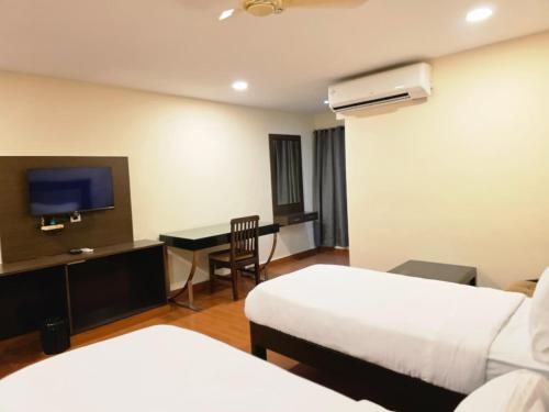 a hotel room with two beds and a desk at MG Beatle Hotel Tirupati in Tirupati