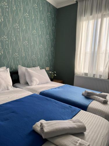 a bedroom with two beds with blue sheets and a window at Hostel Tsalka in Tsalka