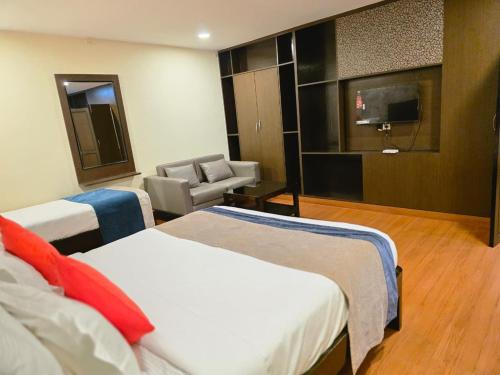 a hotel room with two beds and a television at MG Beatle Hotel Tirupati in Tirupati