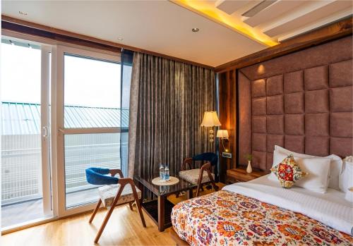 a hotel room with a bed and a balcony at Jr Hotel Dharamshala in Dharamshala