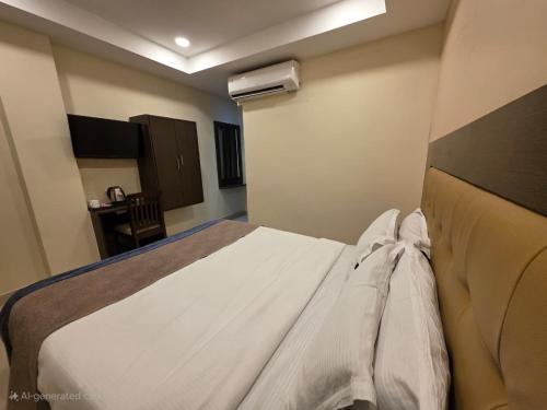 a bedroom with a bed and a chair in it at MG Beatle Hotel Tirupati in Tirupati