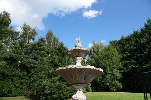 a large stone fountain in a park with trees at Le Grand Jardin in Dalhem