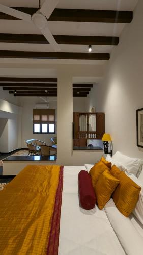a large white bed with yellow and red pillows on it at Nilayam by Luxunlock Private Villas in Jāmb