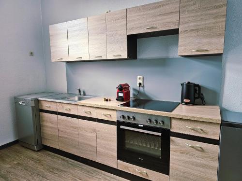 a kitchen with wooden cabinets and a sink and a stove at Haus Sonnenschein in Reuterstadt Stavenhagen