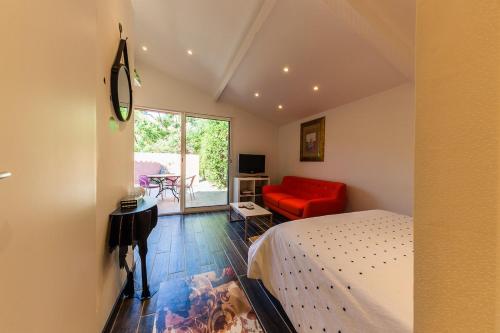 a bedroom with a bed and a red couch at Nice seaside nest with private garden and carpark in Carry-le-Rouet