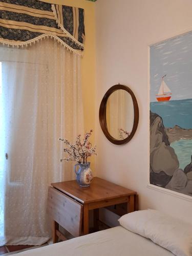 a bedroom with a table and a mirror and a window at B&B IL VECCHIO GELSO in Palinuro