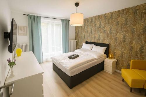 a bedroom with a bed and a yellow chair at Zimmer im besonderem Haus "Columbus" -FjordStay in Kiel