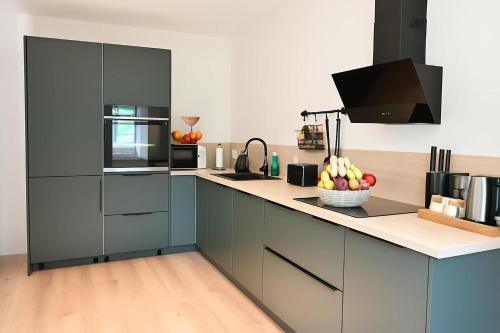 a kitchen with blue cabinets and a bowl of fruit on the counter at Retreat in besonderem Haus "Polo" - FjordStay in Kiel