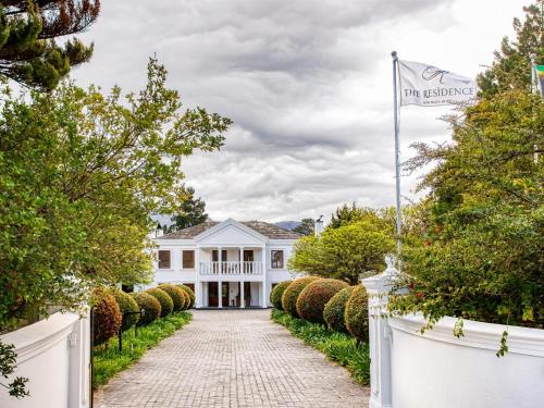 a white house with a white fence and a driveway at The Residence Boutique Hotel in Pineview