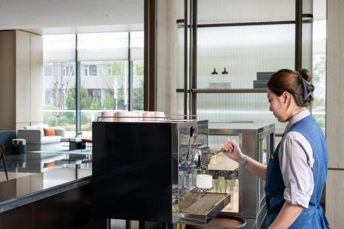 a woman standing in a kitchen preparing food at Holiday Inn Changchun High Tech Zone by IHG in Changchun