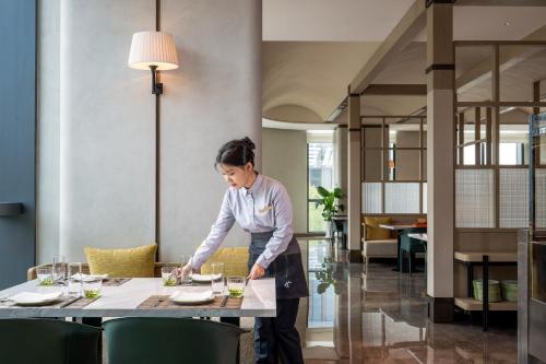 a woman standing at a table in a restaurant at Holiday Inn Changchun High Tech Zone by IHG in Changchun