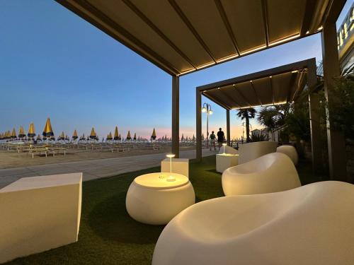 a group of white tables and chairs on the grass at Hotel Nizza Frontemare Superior 3 Stelle in Lido di Jesolo